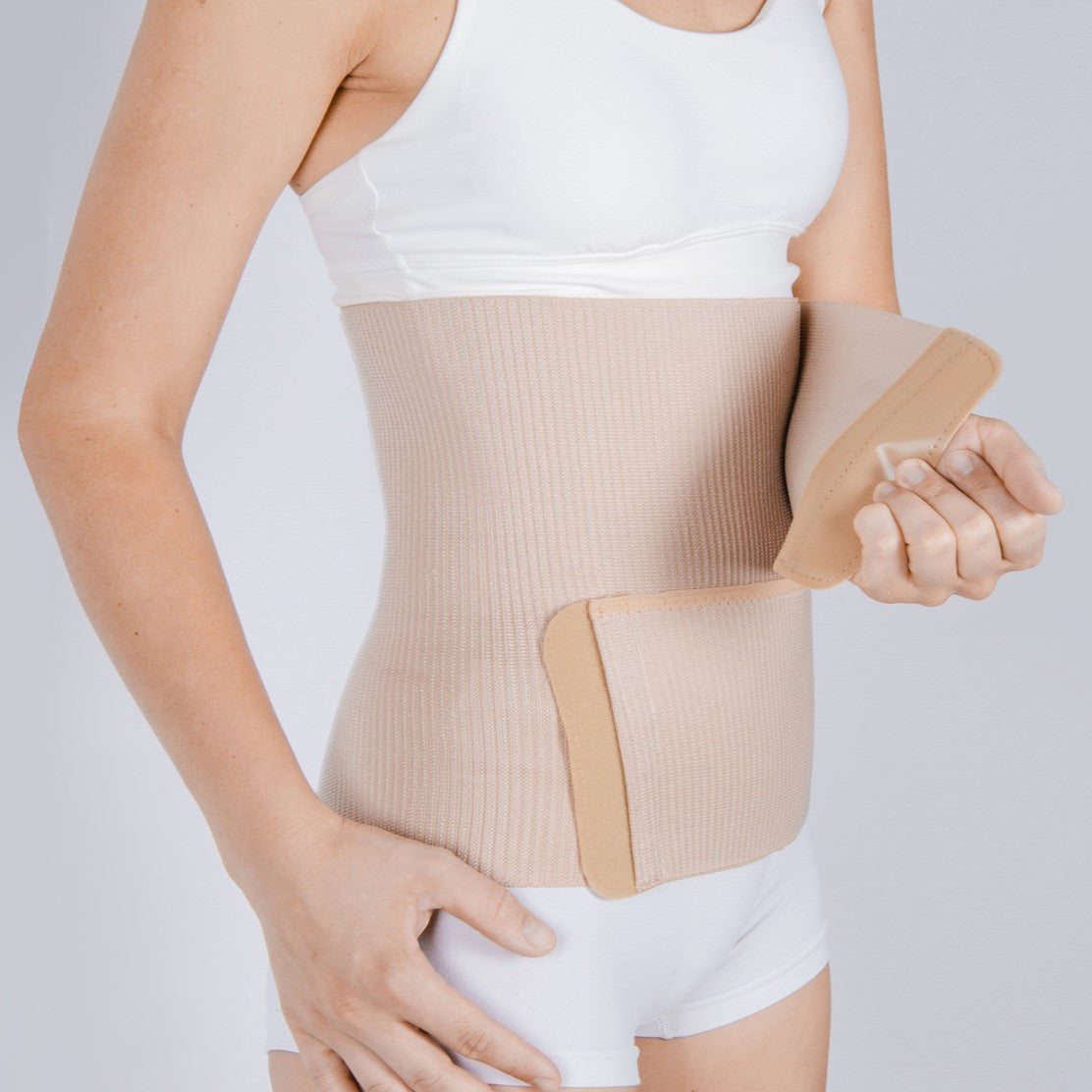A woman wearing a velcro closure abdominal wrap to help reduce hernia symptoms.